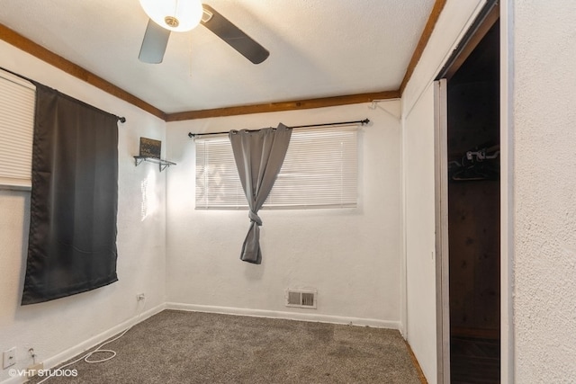 spare room featuring a textured ceiling, carpet, ornamental molding, and ceiling fan