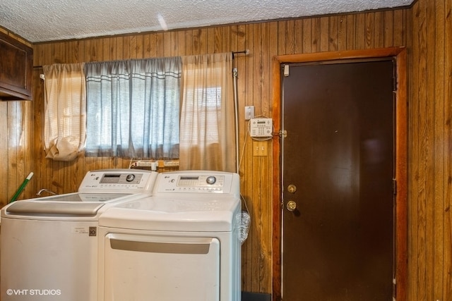 laundry area with a textured ceiling, wooden walls, and washing machine and clothes dryer