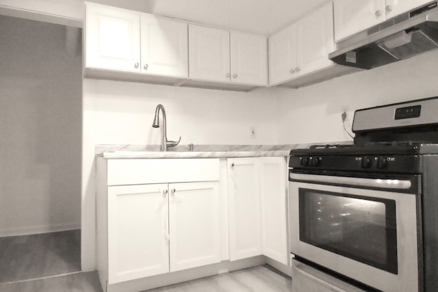 kitchen with stainless steel stove, light hardwood / wood-style flooring, sink, and white cabinetry