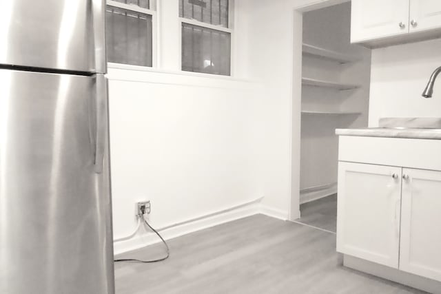 kitchen featuring stainless steel refrigerator, light hardwood / wood-style floors, sink, and white cabinets