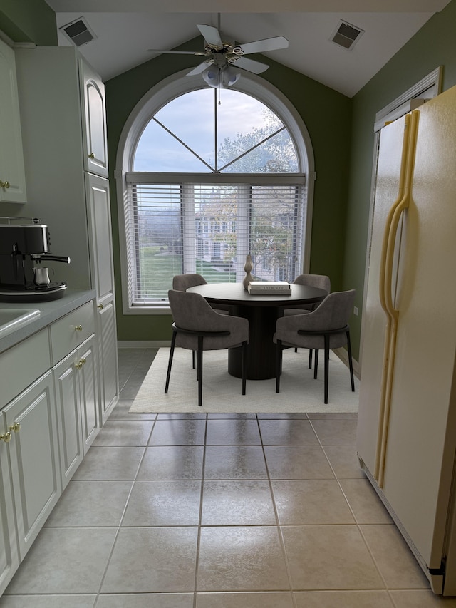 dining room with light tile patterned floors, visible vents, lofted ceiling, and a ceiling fan