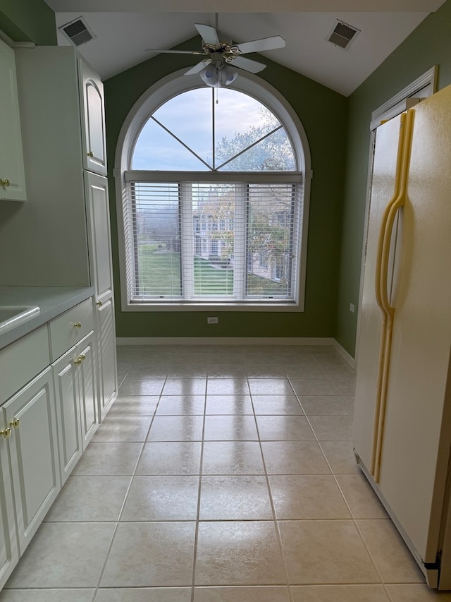 unfurnished dining area featuring light tile patterned flooring, visible vents, ceiling fan, and vaulted ceiling