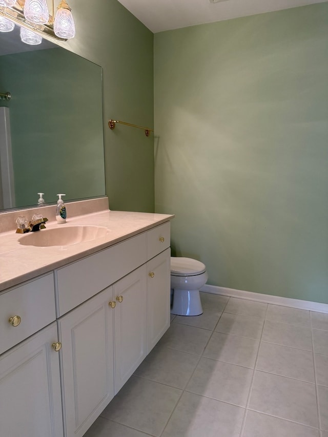 bathroom with toilet, vanity, and tile patterned flooring