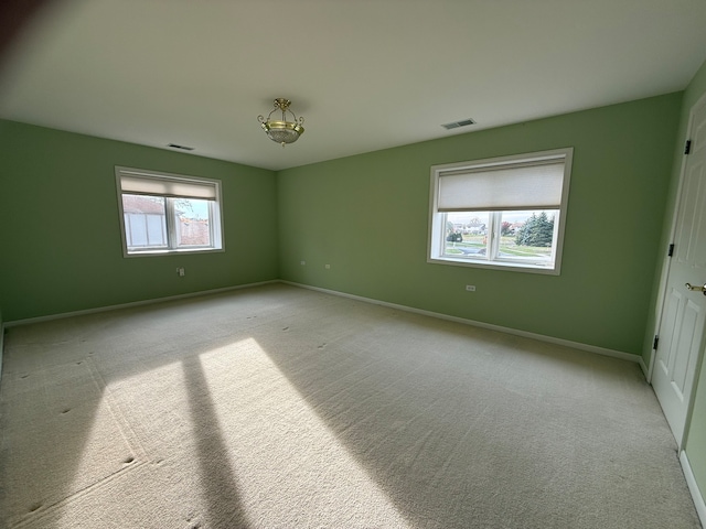 empty room with visible vents, baseboards, and light colored carpet