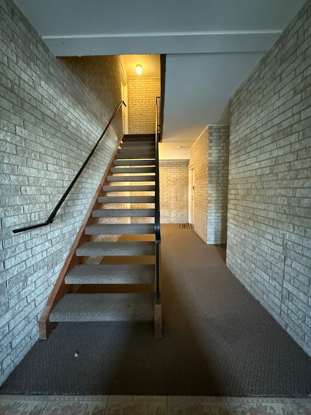 staircase with carpet flooring and brick wall