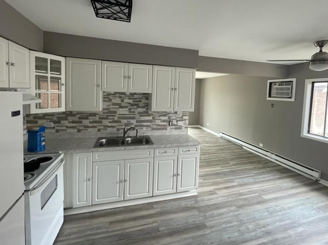 kitchen featuring white appliances, tasteful backsplash, sink, a baseboard radiator, and white cabinetry