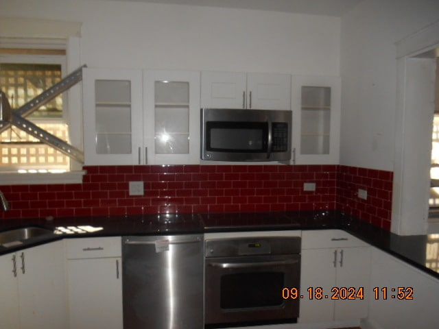 kitchen with decorative backsplash, white cabinetry, sink, and stainless steel appliances