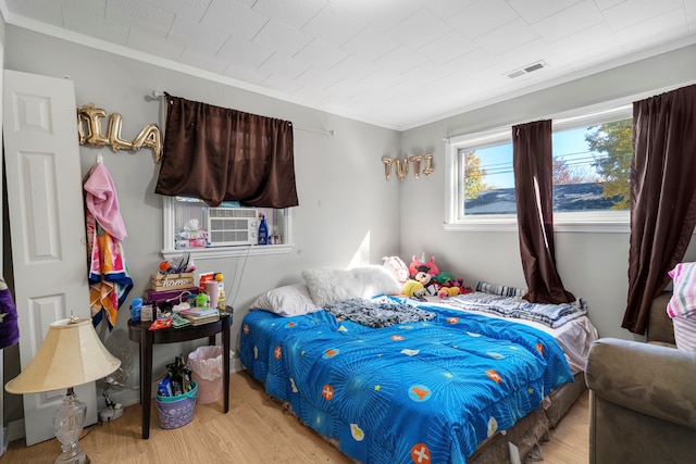 bedroom featuring crown molding, light hardwood / wood-style flooring, and cooling unit