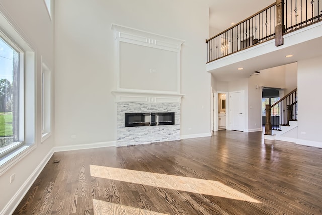 unfurnished living room with a towering ceiling and dark hardwood / wood-style flooring