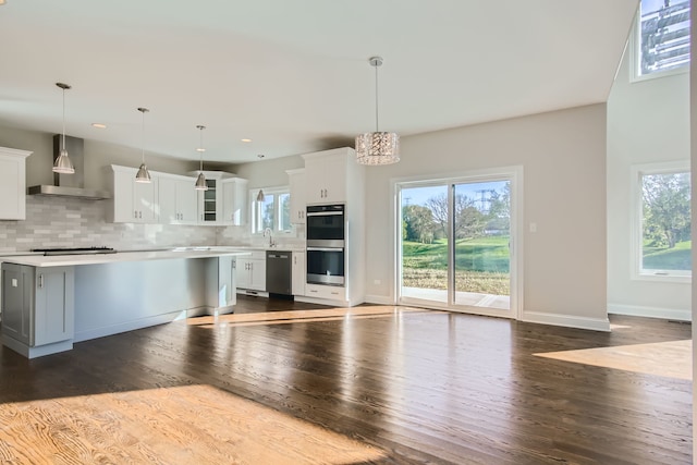 kitchen featuring pendant lighting, white cabinetry, and wall chimney range hood