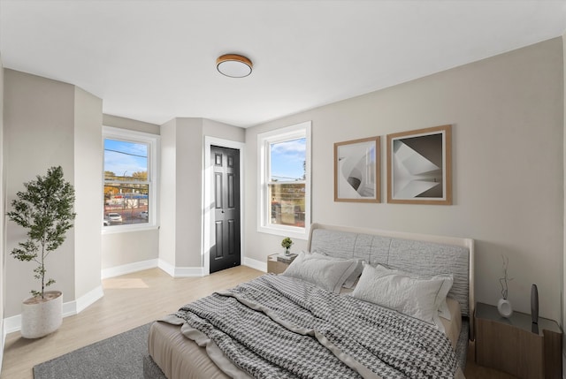 bedroom with light hardwood / wood-style floors and multiple windows