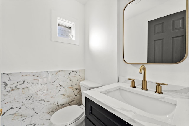 bathroom with tile walls, vanity, and toilet