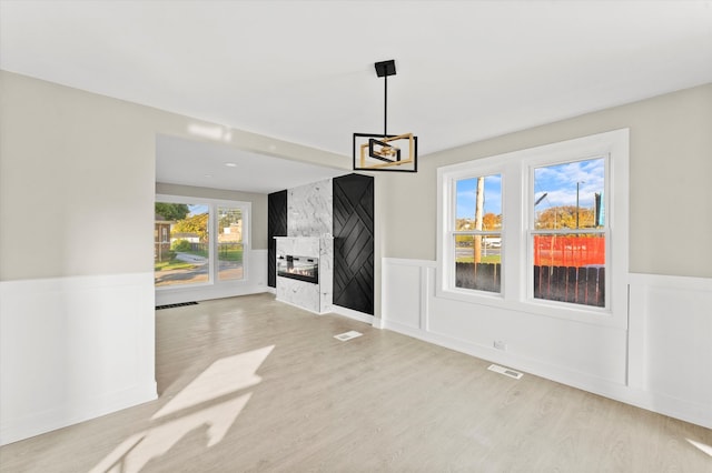 unfurnished dining area with a fireplace and light hardwood / wood-style floors