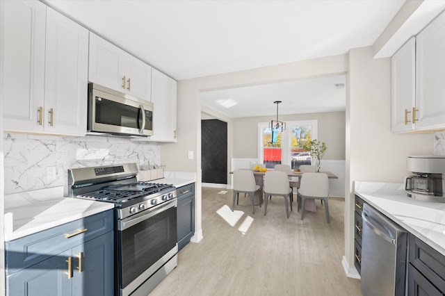 kitchen featuring decorative backsplash, light stone countertops, white cabinetry, appliances with stainless steel finishes, and light hardwood / wood-style floors