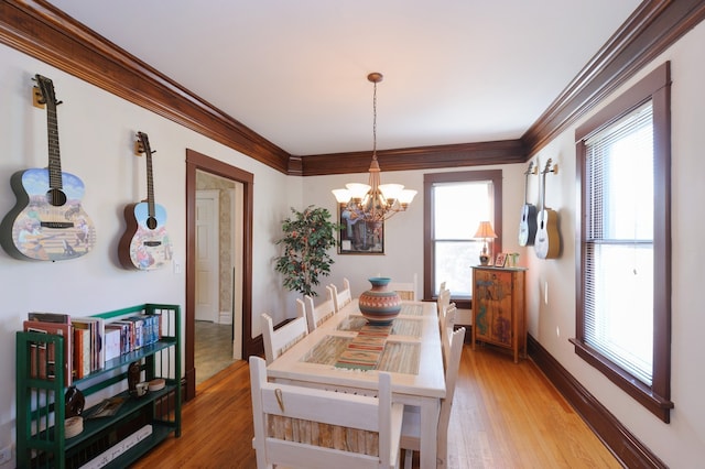 dining area featuring light wood-type flooring, crown molding, and a healthy amount of sunlight