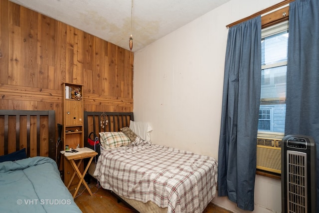 bedroom featuring wood walls, hardwood / wood-style floors, and heating unit