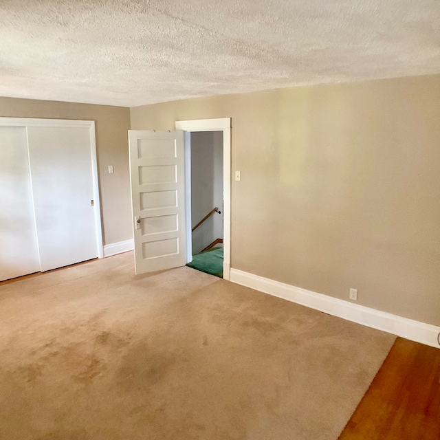 unfurnished bedroom with carpet floors, a textured ceiling, and a closet