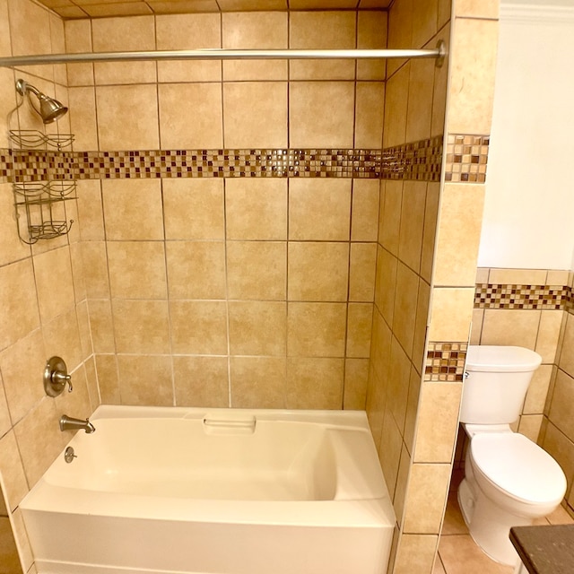 bathroom with tile walls, tiled shower / bath combo, tile patterned floors, and toilet