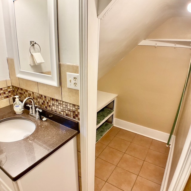 bathroom featuring vanity, vaulted ceiling, tasteful backsplash, and tile patterned floors