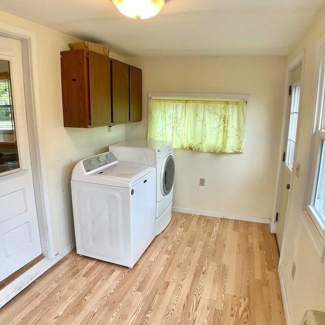 washroom with washing machine and dryer, light hardwood / wood-style flooring, and cabinets