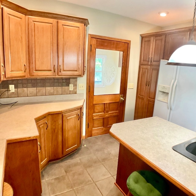 kitchen featuring decorative light fixtures, light tile patterned flooring, white refrigerator with ice dispenser, and tasteful backsplash