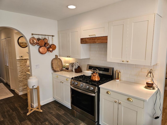 kitchen featuring stainless steel range with gas cooktop, backsplash, white cabinetry, and dark hardwood / wood-style floors