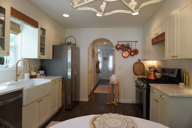 kitchen with appliances with stainless steel finishes, decorative backsplash, dark wood-type flooring, and white cabinets