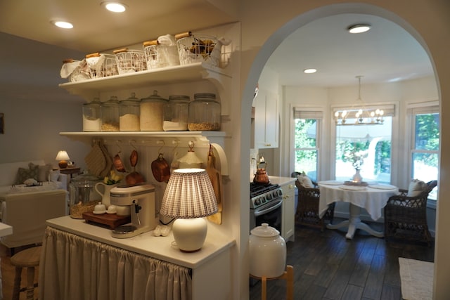 kitchen with stainless steel stove, pendant lighting, an inviting chandelier, and dark wood-type flooring