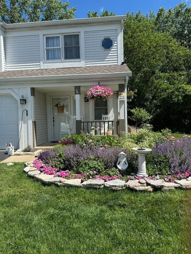 view of exterior entry with a lawn, a garage, and covered porch