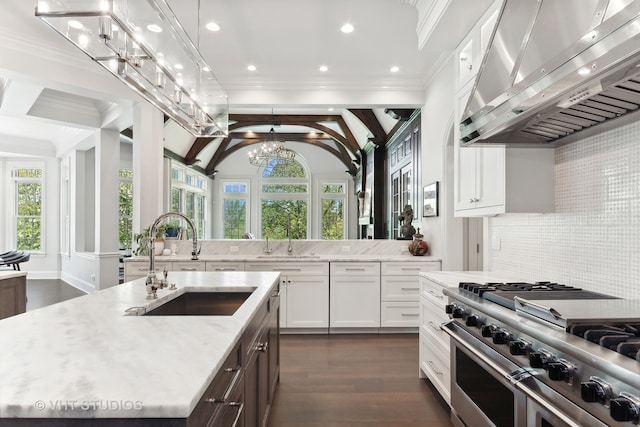 kitchen featuring wall chimney exhaust hood, plenty of natural light, high end range, and a kitchen island with sink