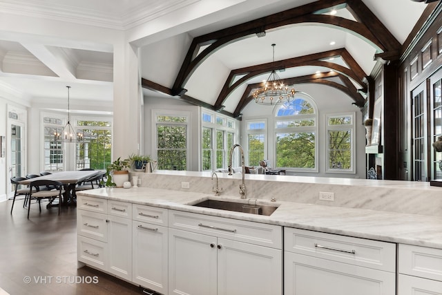 kitchen featuring lofted ceiling with beams, light stone counters, white cabinets, sink, and a chandelier