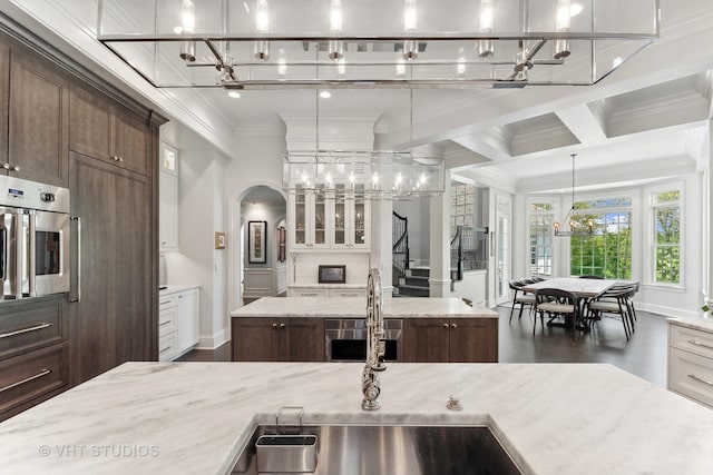 kitchen with stainless steel oven, light stone countertops, hanging light fixtures, white cabinets, and a large island