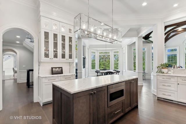 kitchen with dark brown cabinets, crown molding, white cabinetry, dark hardwood / wood-style floors, and stainless steel microwave