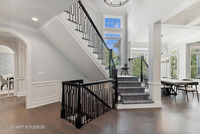 stairs featuring crown molding, hardwood / wood-style floors, and an inviting chandelier