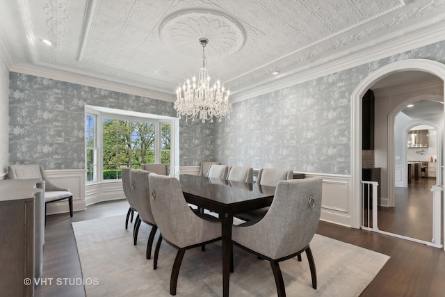 dining space with ornamental molding, a notable chandelier, and dark hardwood / wood-style flooring