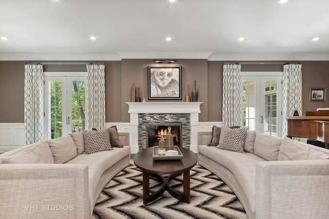 living room with french doors, ornamental molding, and a tile fireplace