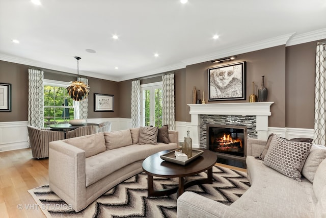 living room with light wood-type flooring, crown molding, and a tile fireplace