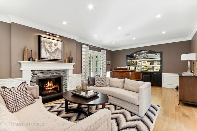 living room with ornamental molding, light wood-type flooring, and a tile fireplace