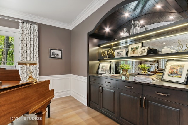 bar featuring dark brown cabinets, light hardwood / wood-style floors, and ornamental molding