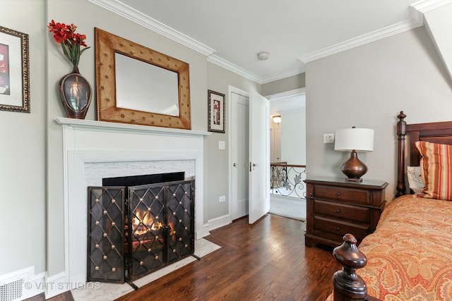 bedroom featuring a premium fireplace, ornamental molding, and dark hardwood / wood-style floors