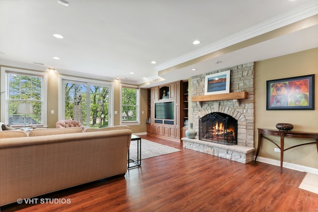 unfurnished living room with ornamental molding, a stone fireplace, and wood-type flooring