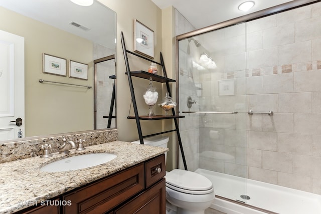 bathroom featuring a shower with shower door, vanity, and toilet