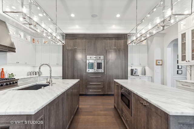 kitchen with sink, light stone counters, dark hardwood / wood-style floors, appliances with stainless steel finishes, and a spacious island