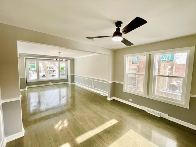 unfurnished room featuring ceiling fan with notable chandelier, hardwood / wood-style flooring, and a wealth of natural light