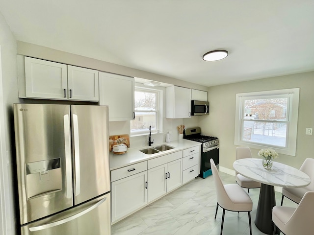 kitchen featuring appliances with stainless steel finishes, white cabinetry, and sink