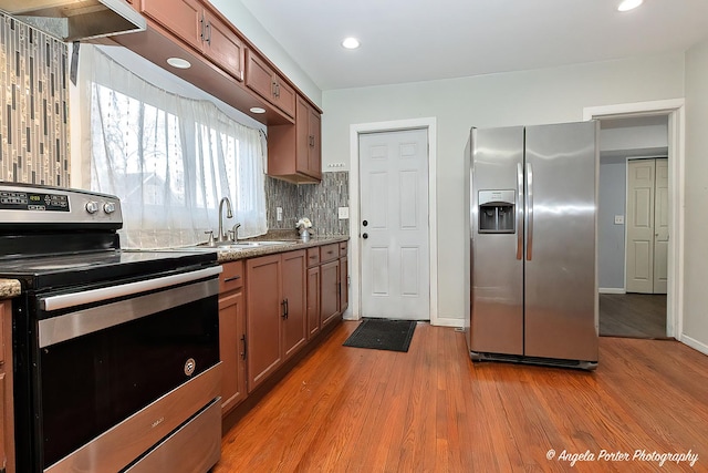 kitchen with light hardwood / wood-style floors, light stone countertops, sink, and appliances with stainless steel finishes