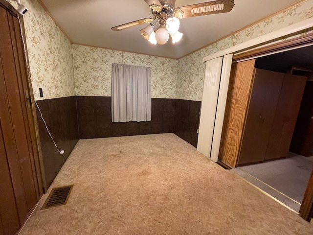 unfurnished room featuring ceiling fan, carpet floors, and wooden walls