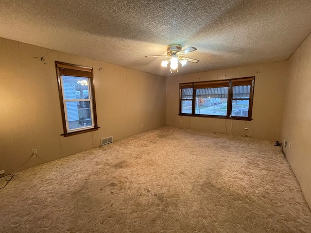 carpeted spare room featuring ceiling fan and a textured ceiling