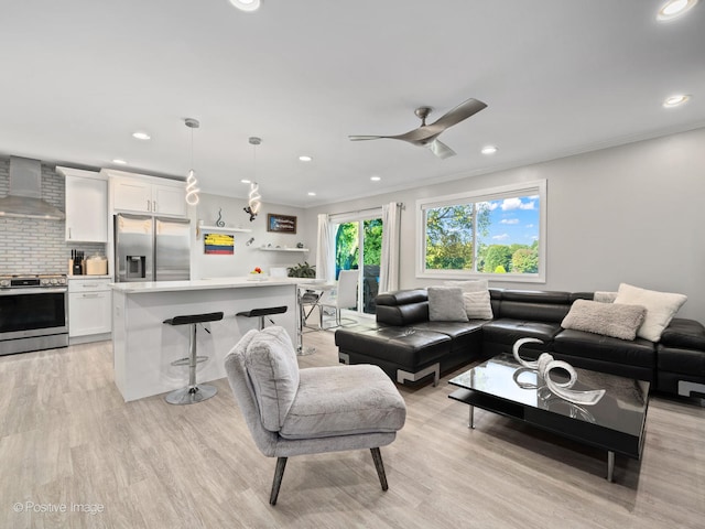 living room featuring light hardwood / wood-style flooring, ceiling fan, and crown molding