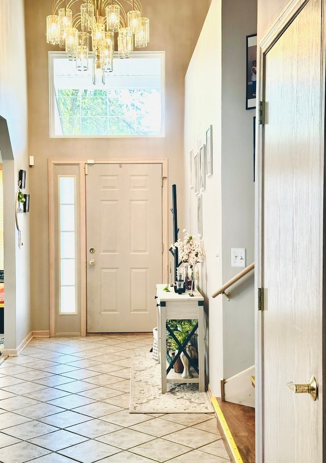 entryway featuring a towering ceiling, a healthy amount of sunlight, light tile patterned floors, and a notable chandelier